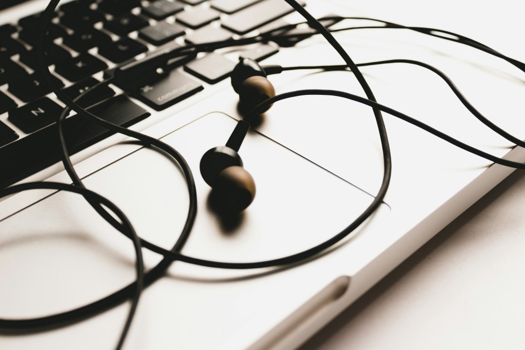 A close up of a laptop mousepad and keyboard with headphones strewn on top.